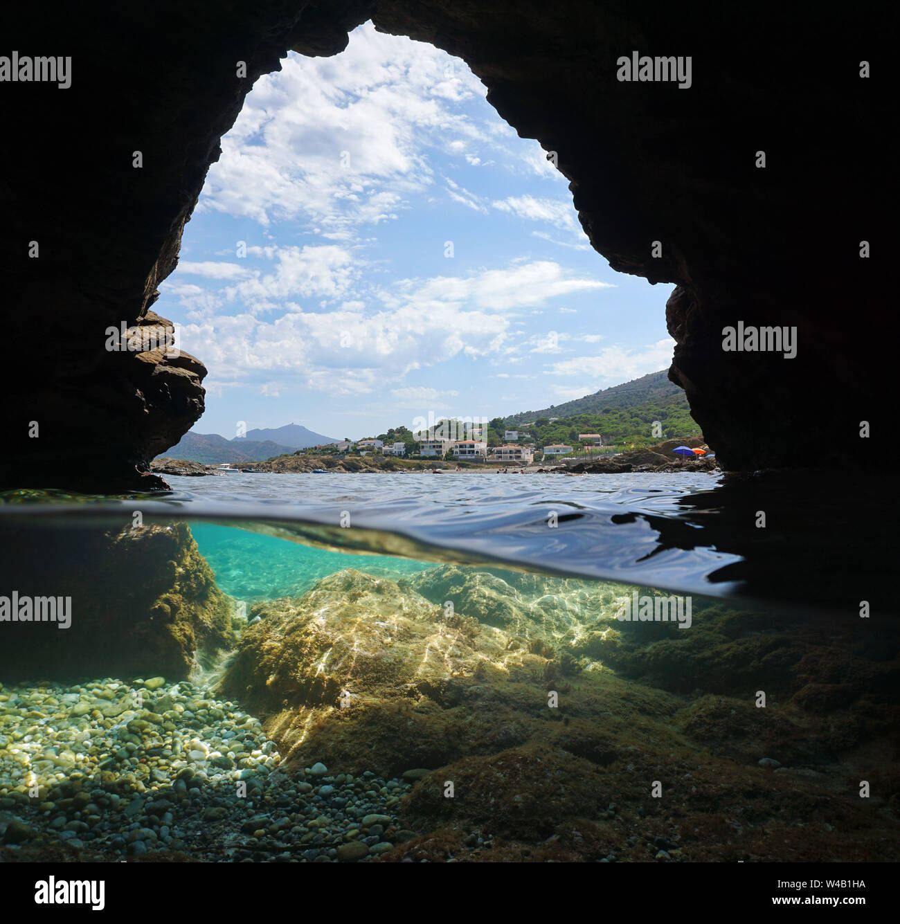 Costa desde el interior de una cueva en la orilla del mar, vista dividida sobre y bajo el agua, el mar Mediterráneo, España, el Port de la Selva, Costa Brava, Cataluña Foto de stock