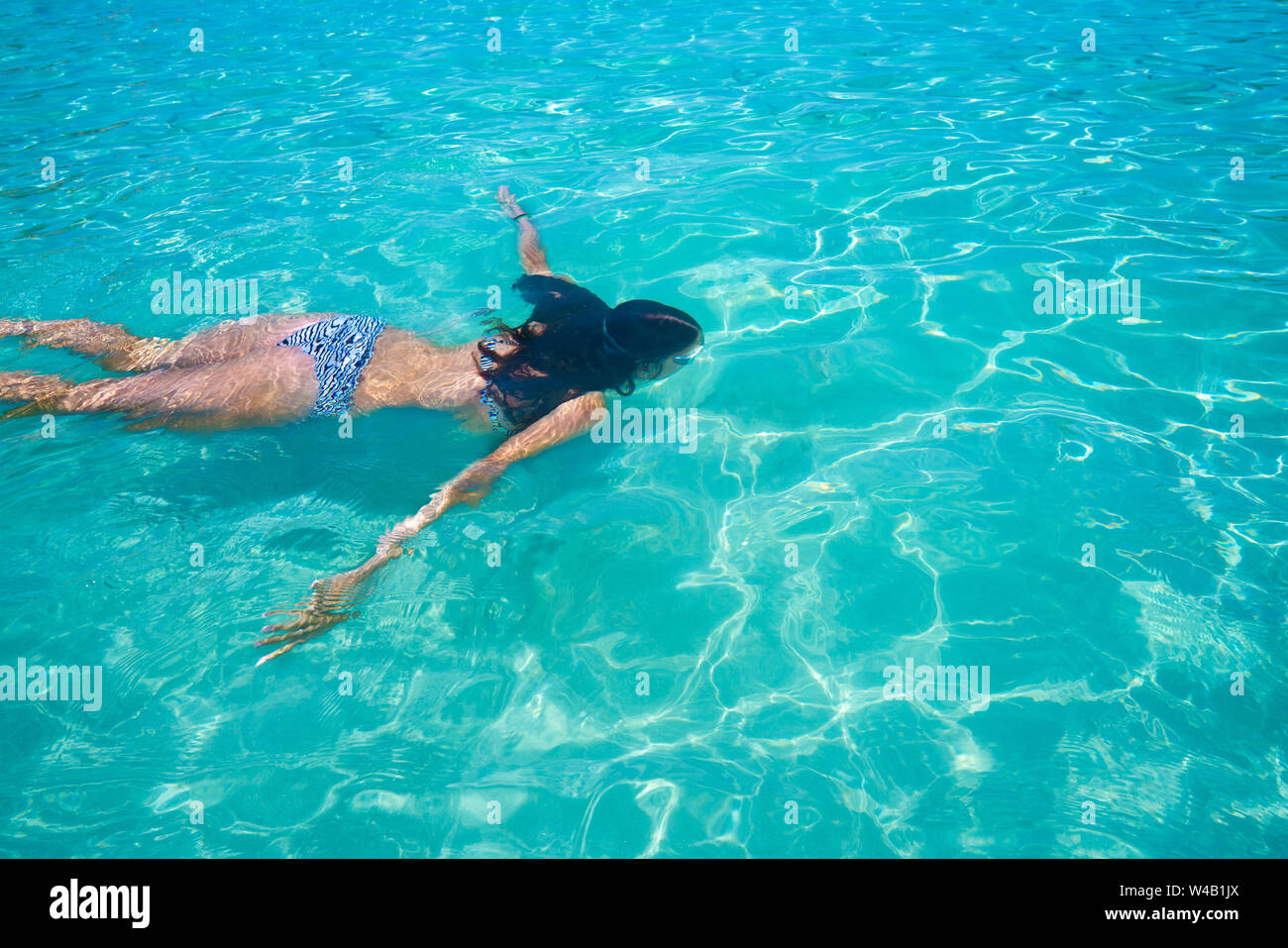 Bikini chica nadando en clara Ibiza playa tropical mediterráneo turquesa Foto de stock