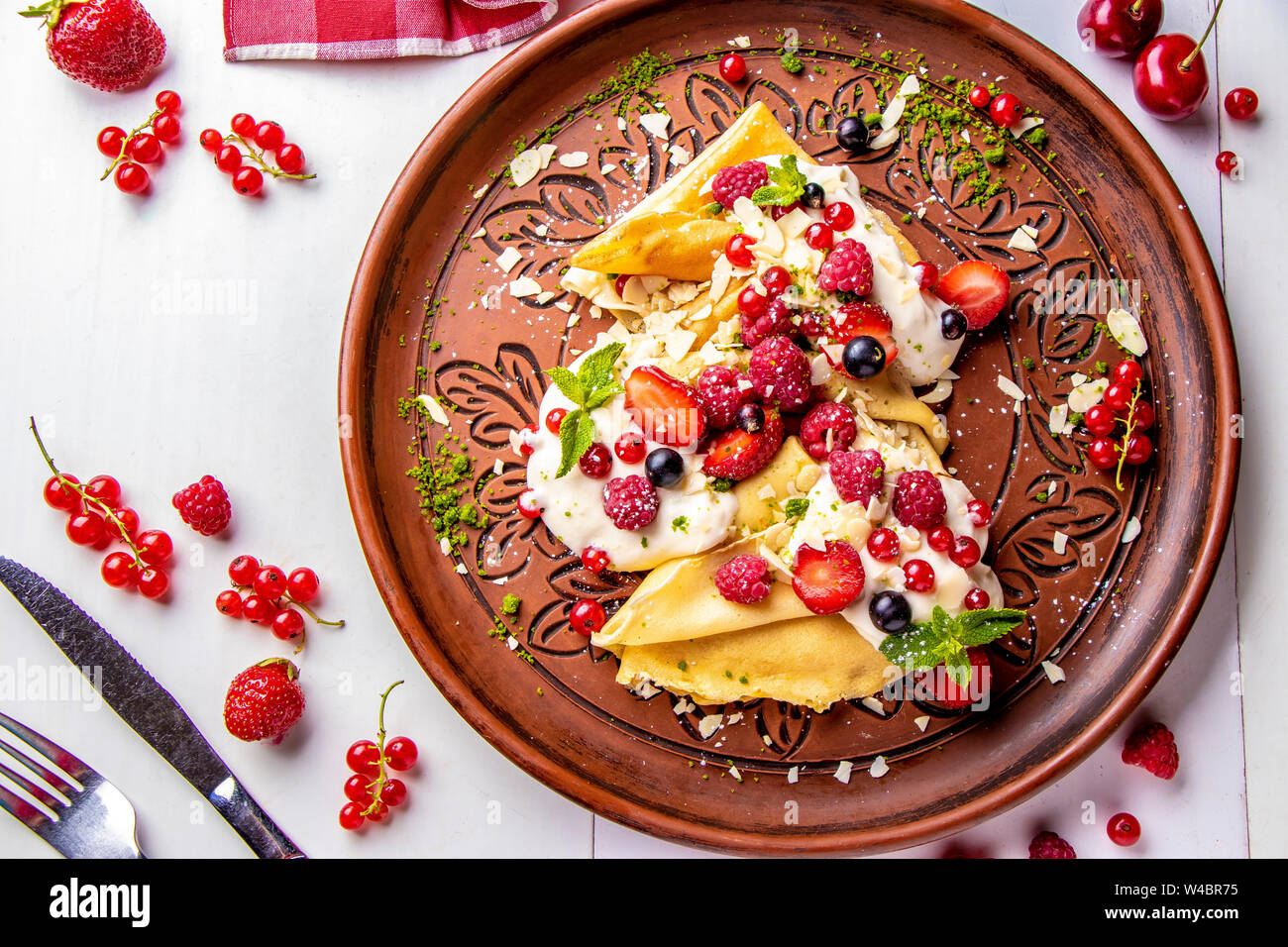 Tortitas caseras con crema agria y bayas sobre un fondo blanco de cerca, la foto en horizontal, vista superior Foto de stock