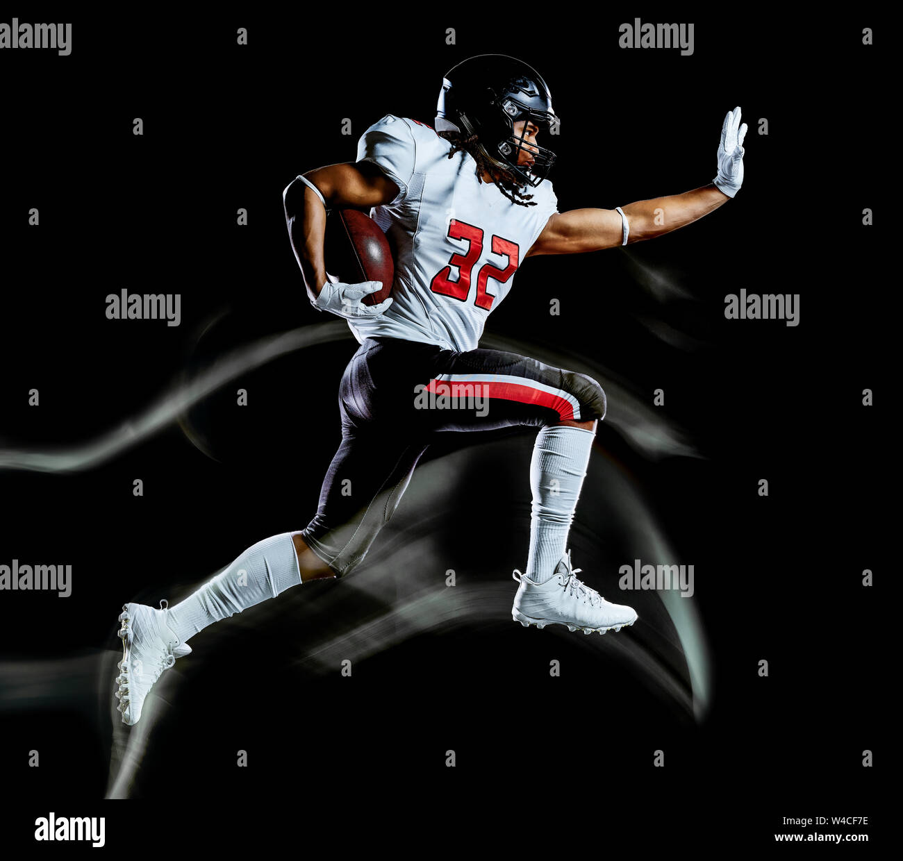 Un jugador de fútbol afroamericano hombre Foto de estudio aislado sobre fondo negro con pintura de luz con el efecto de la velocidad de movimiento borrosa Foto de stock