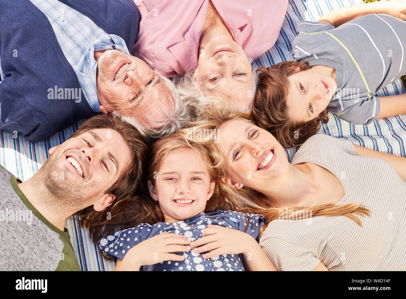 Feliz familia con dos hijos con abuelos recae conjuntamente en círculo Foto de stock