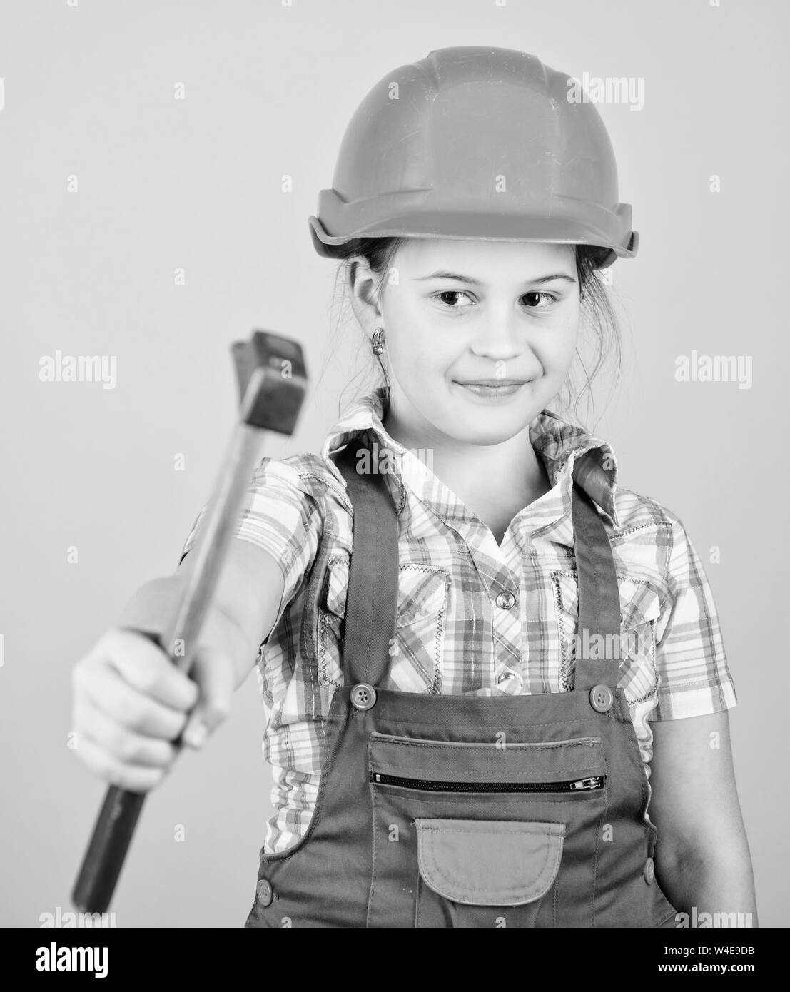 El día del trabajo. El 1 de mayo. taller de reparación. con un martillo en  la mano de la niña pequeña reparación en taller. Foreman inspector. Niña en  el casco con un