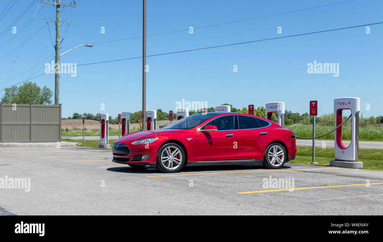 Rojo modelo Tesla S conectado y la carga en Tesla Supercharger estación