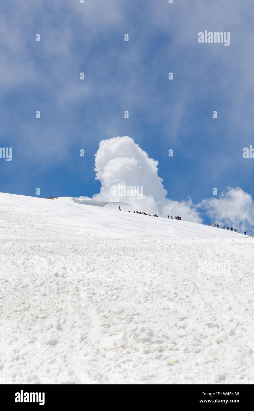Diminutas figuras de seres humanos caminando lejos en el paisaje lleno de nieve blanca en Pico Apharwat Gulmarg, Jammu y Cachemira, la India Foto de stock