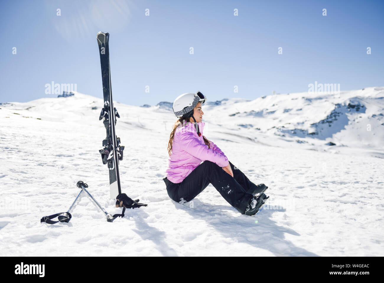 Mujer Con El Pelo Largo Oscuro Tomando Un Descanso Del Esquí Y Sentado En  La Nieve Para Disfrutar Del Cálido Sol Sobre La Nieve Cubre La Ladera  Fotos, retratos, imágenes y fotografía