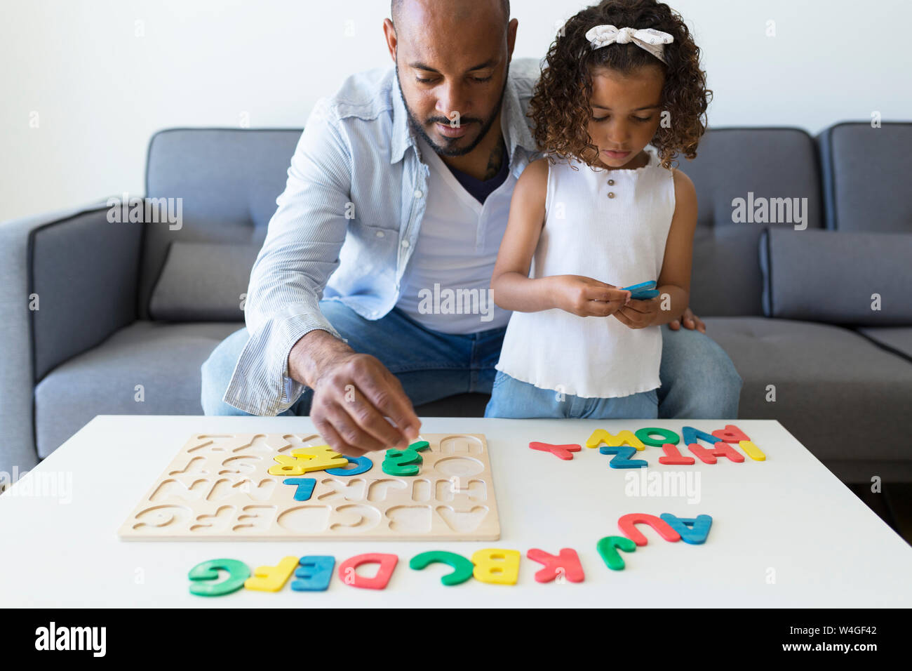 Padre e hija jugar con el alfabeto juego didáctico en casa Foto de stock