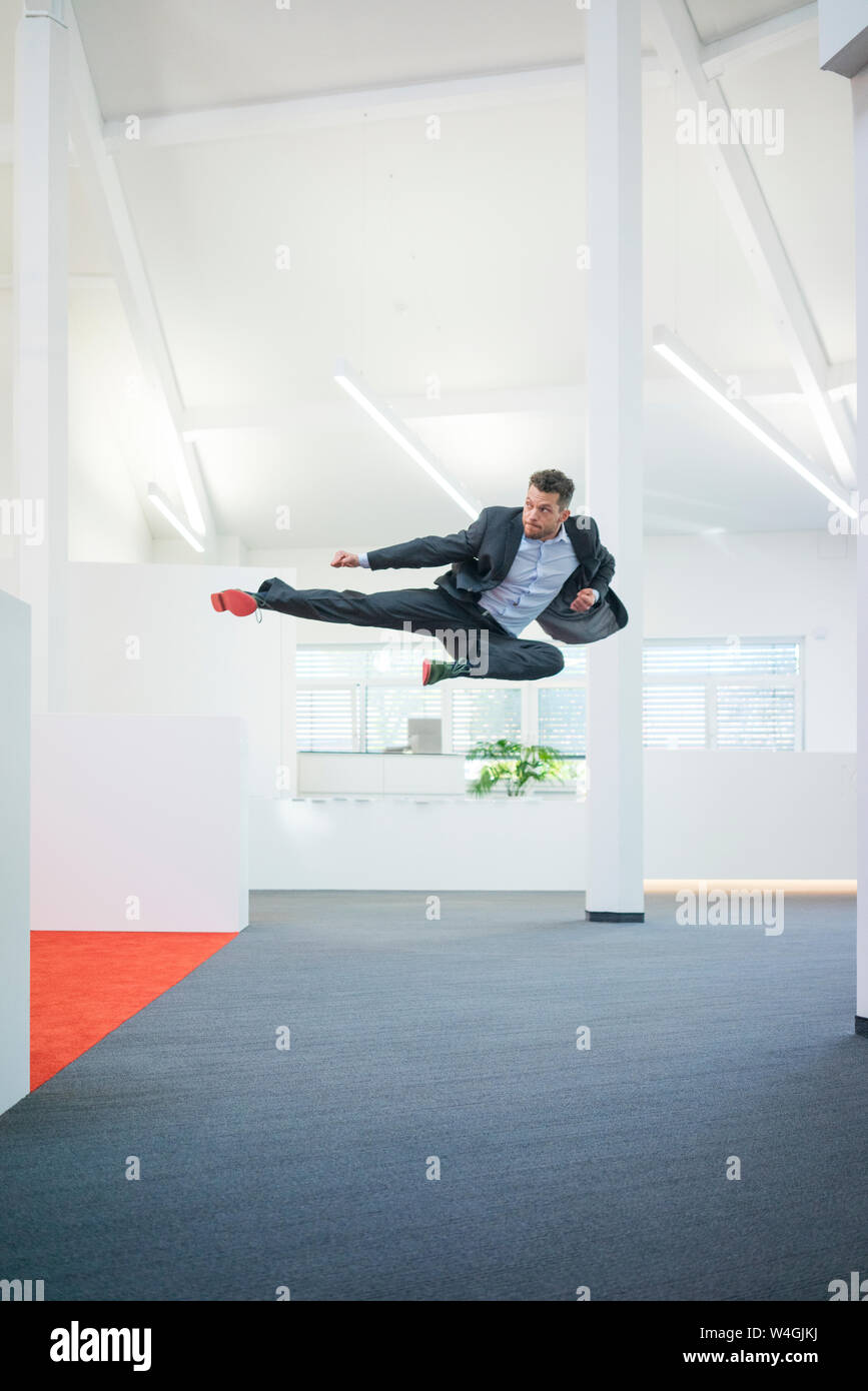 Empresario saltar en mitad del aire sobre el suelo de su oficina Foto de stock
