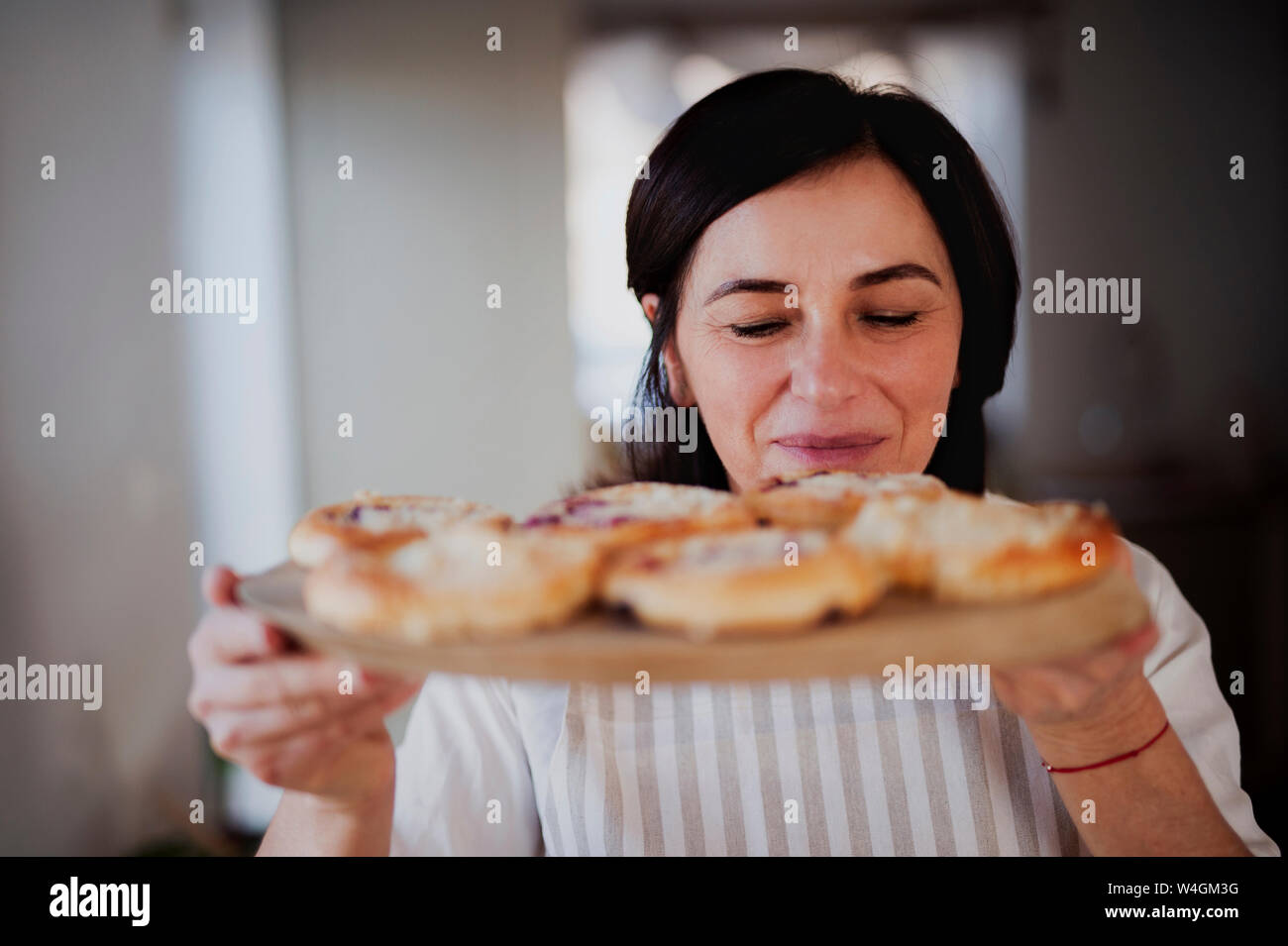 Mujer madura que sirve tartas caseras ona bandeja de madera Foto de stock