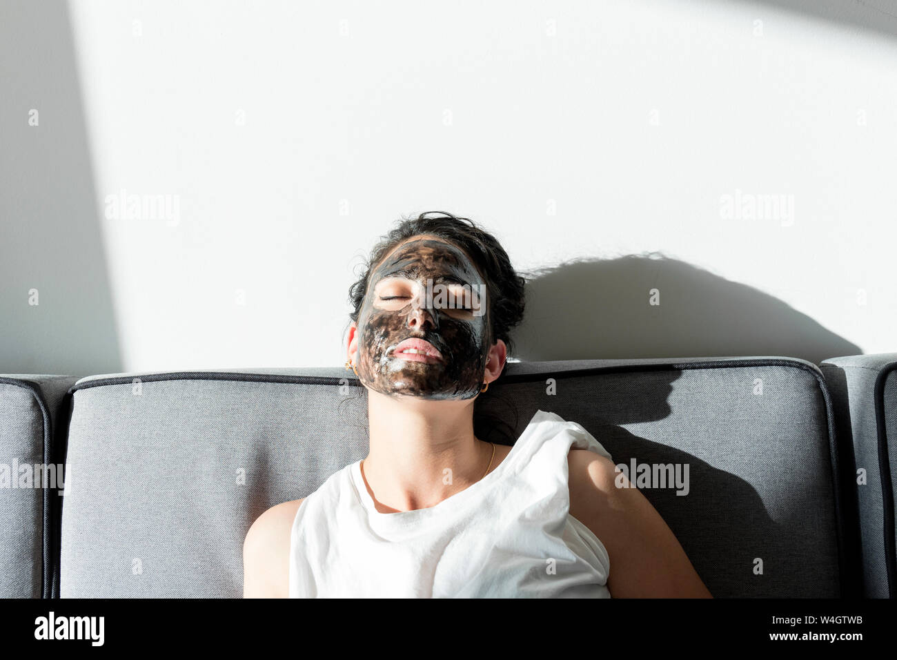 Relajado Joven vistiendo máscara facial en casa Foto de stock