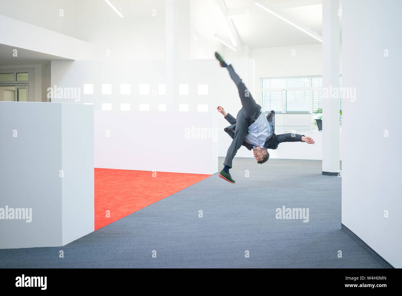 Empresario saltar en mitad del aire sobre el suelo de su oficina Foto de stock