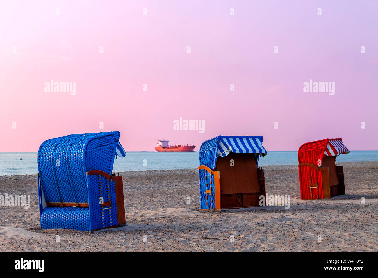 Tres encapuchados, sillas de playa, al atardecer, Warnemuende, Rostock, Alemania Foto de stock