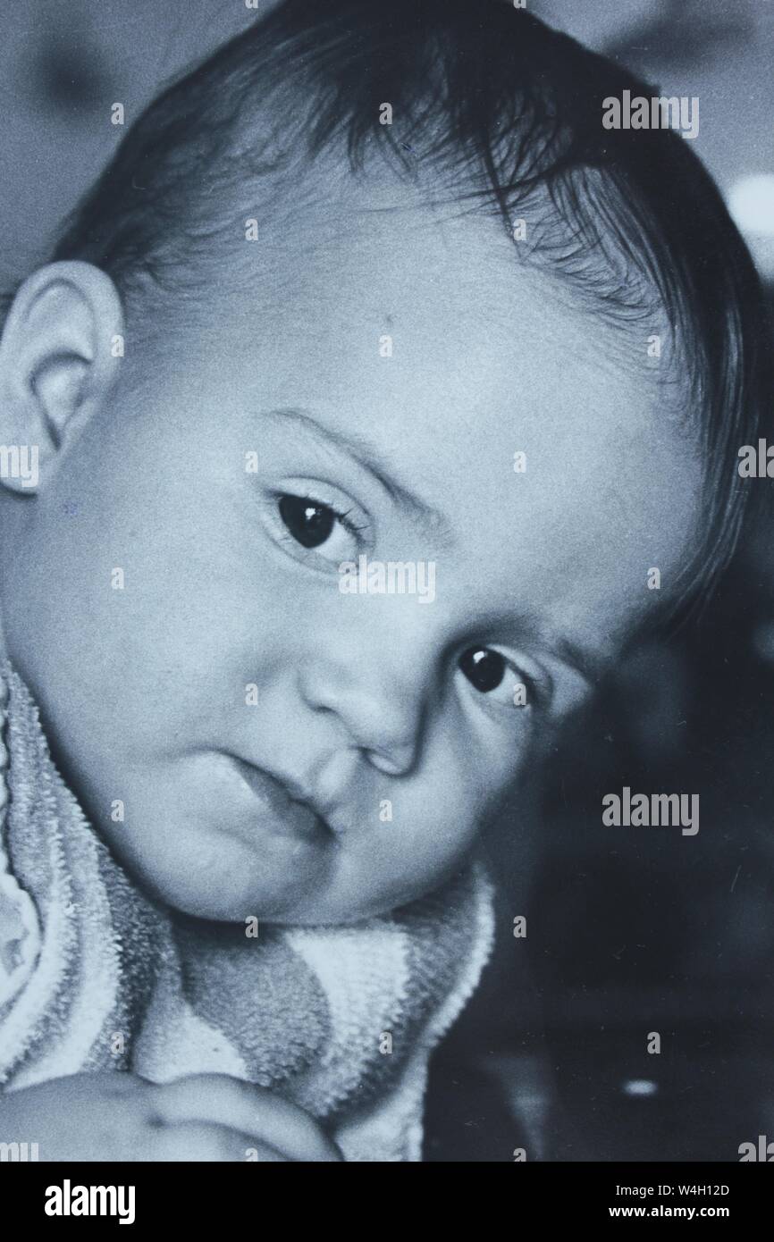 Fino arte fotografía en blanco y negro a partir de la década de 1970 de un bebé con una mirada curiosa. Foto de stock