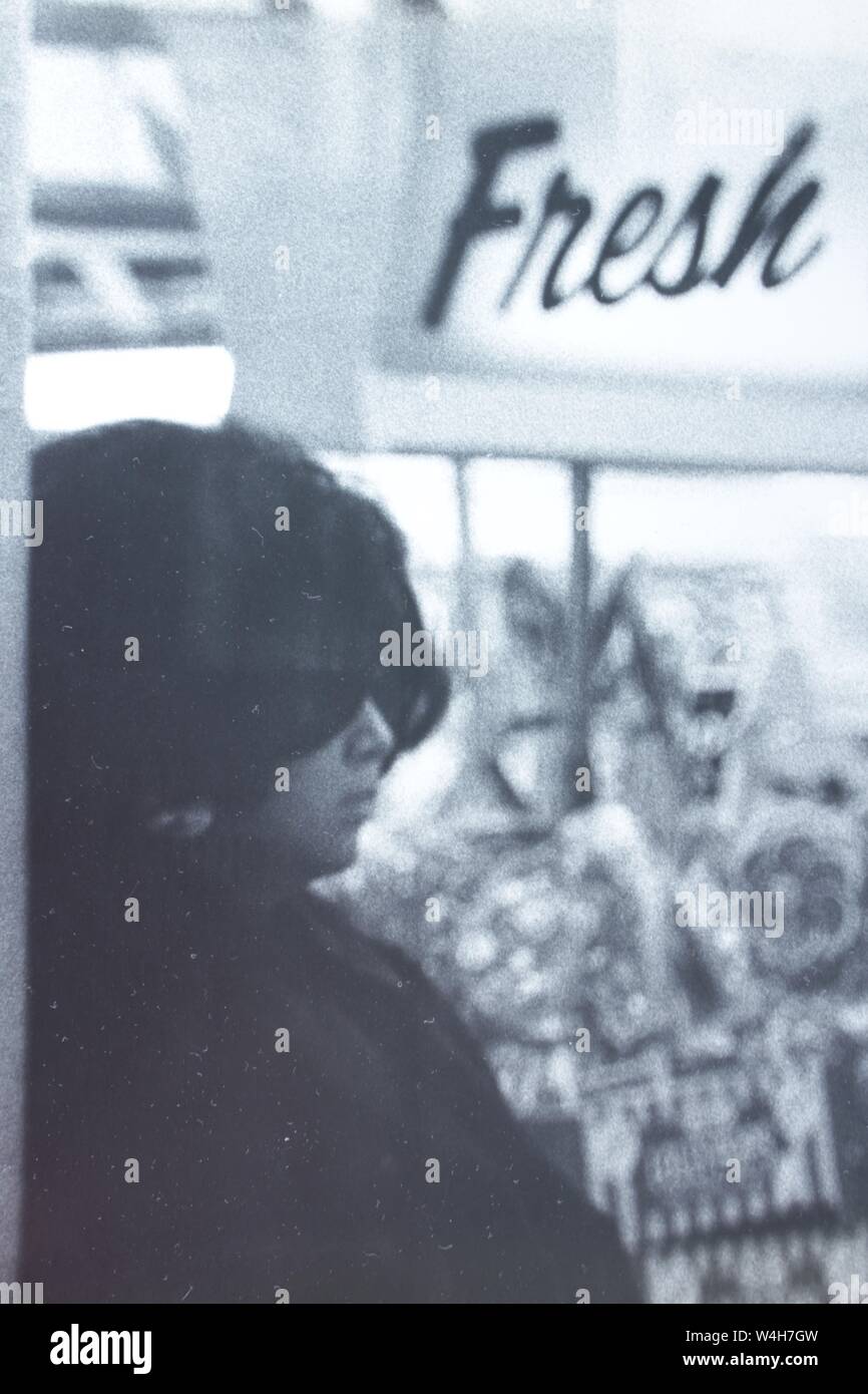 Fino arte fotografía en blanco y negro a partir de la década de 1970 de una elegante mujer de incógnito con un par de gafas de sol oscuras pesado pasando un signo "fresco". Foto de stock