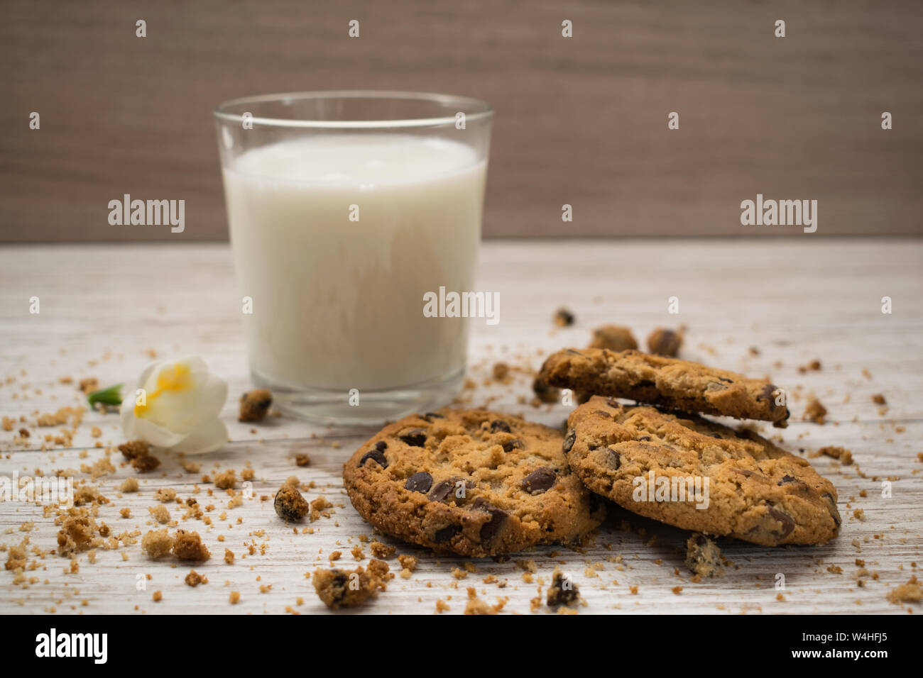 Las galletas con trocitos de chocolate, migas y un vaso de leche sobre una mesa de madera. Estilo Rural Foto de stock