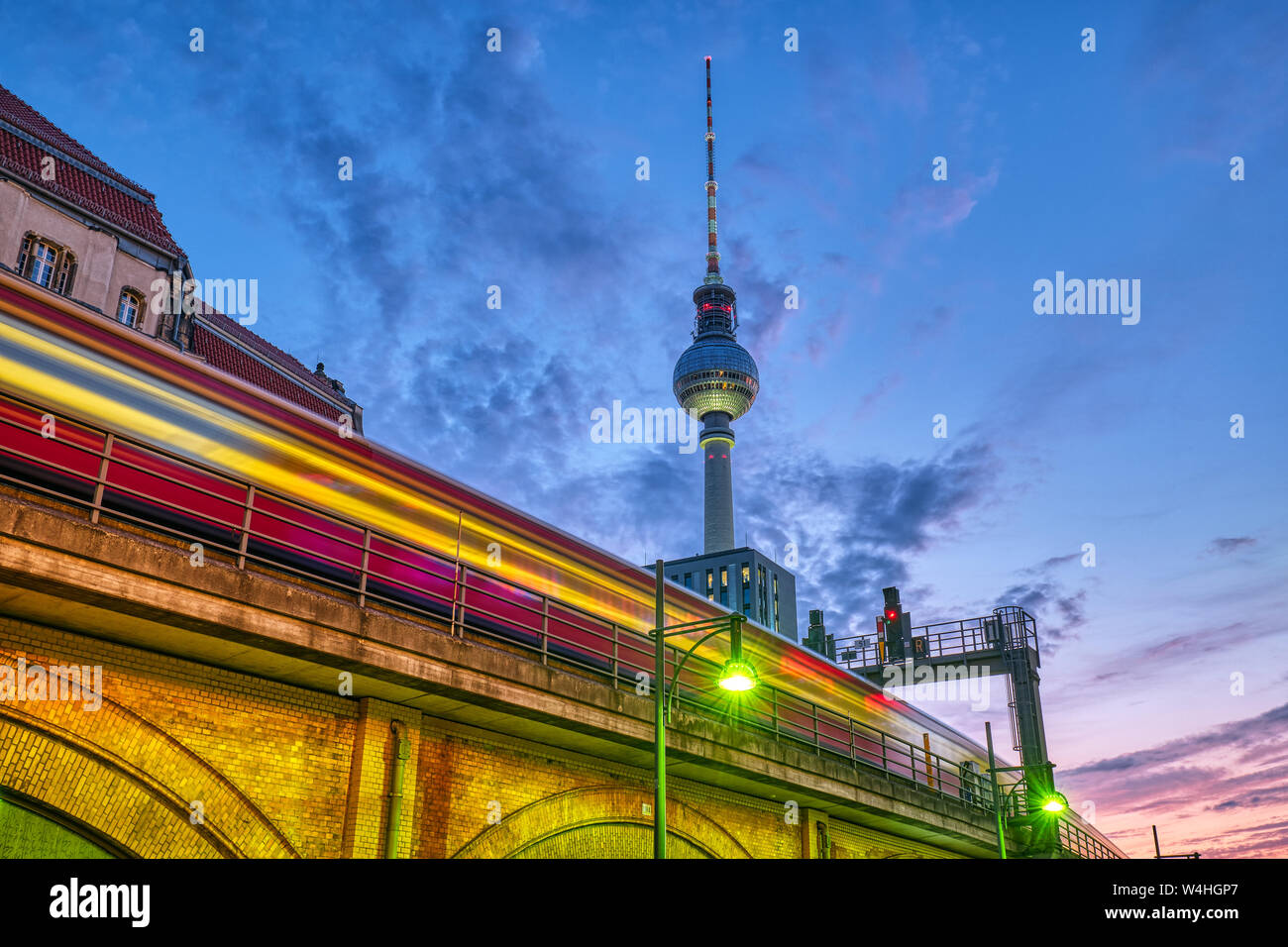 El tren local con el desenfoque de movimiento y la famosa Torre de Televisión de Berlín en la noche Foto de stock