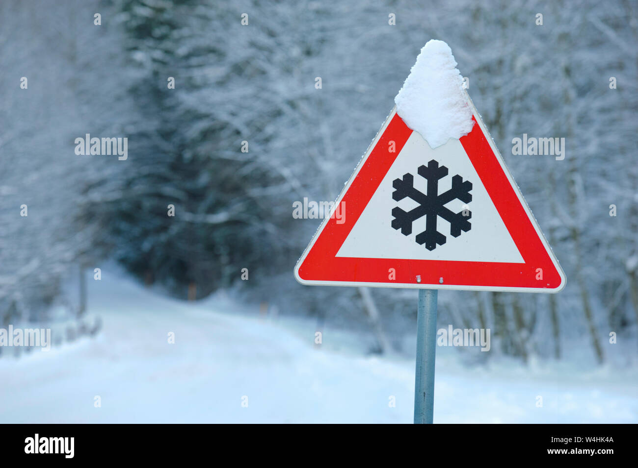 Señal de tráfico en la carretera advierte de hielo y nieve en invierno Foto de stock