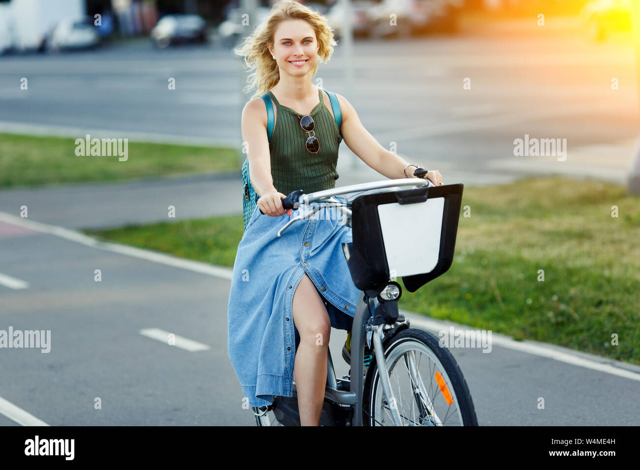 Foto de feliz rubia de larga falda denim montando bicicleta en carretera en  ciudad en día de verano Fotografía de stock - Alamy