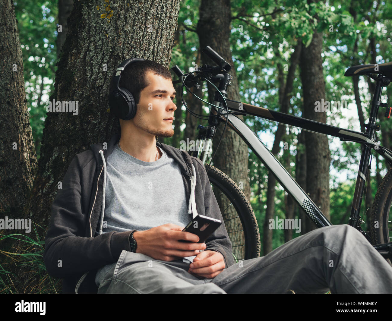Hipster hombre escuchando música en auriculares en la calle , un estilo de vida activo. Andar en bicicleta Foto de stock