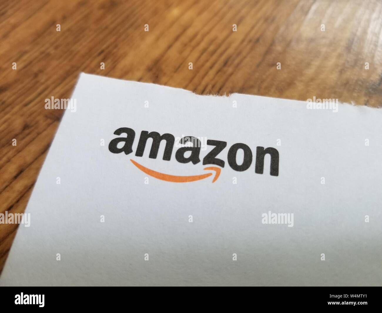 Close-up de logotipo para empresa de comercio electrónico Amazon en un libro blanco contra una superficie de madera ligera, 7 de julio de 2019. () Foto de stock