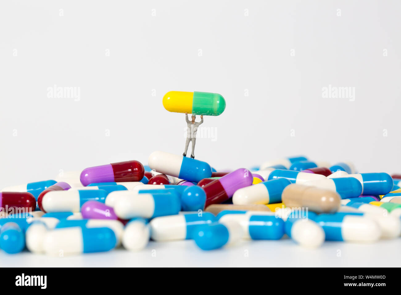 Montón de píldoras de medicina con gente en miniatura sobre fondo blanco Foto de stock