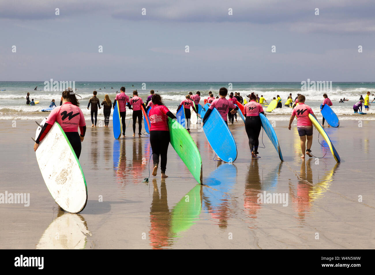 Polzeath, Cornualles, en el Reino Unido. El 24 de julio de 2019. A la cabeza de los surfistas sobre las olas en una tarde soleada y caliente en Polzeath playa en el norte de la costa atlántica de Cornualles. Foto de stock