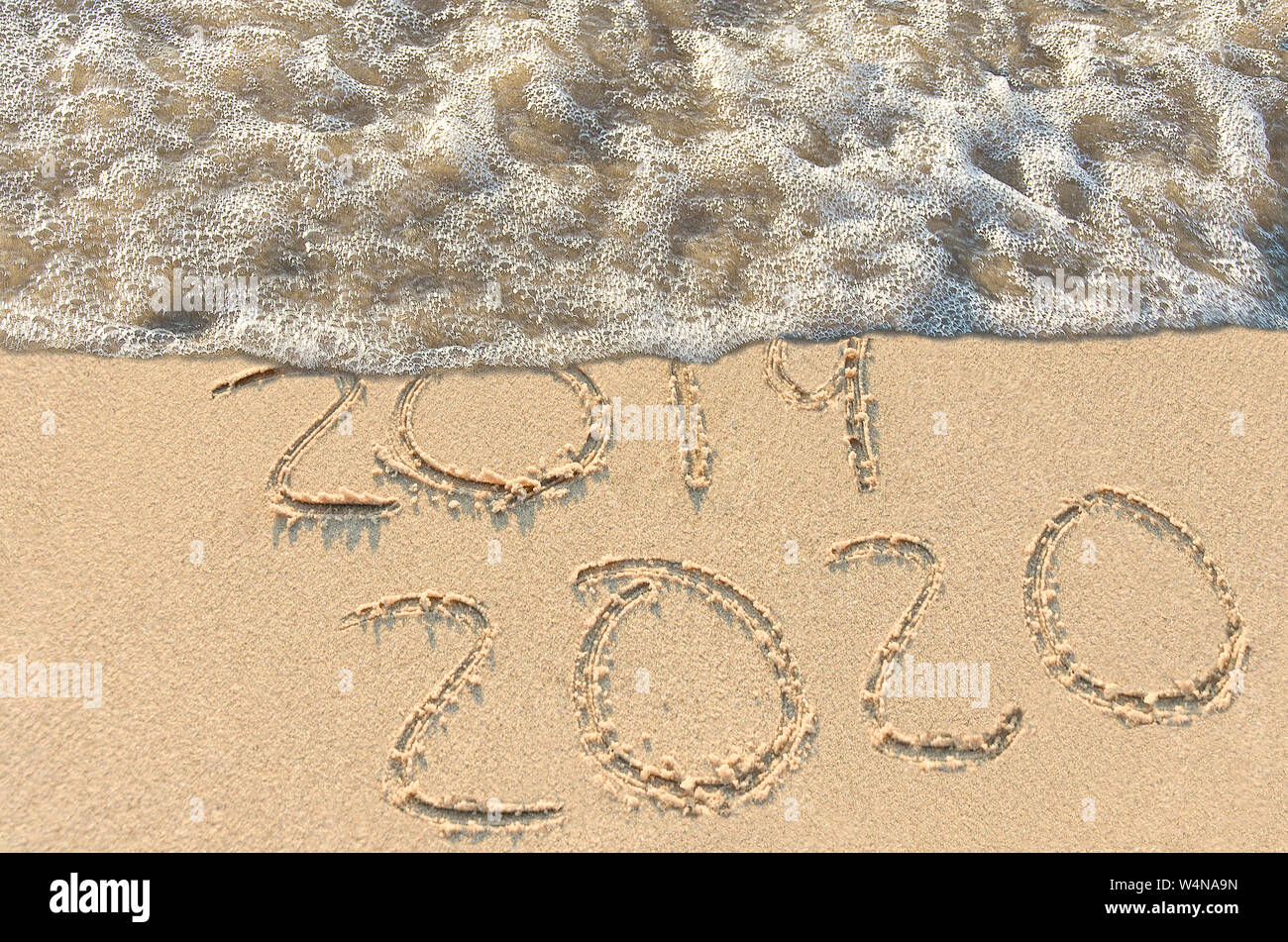 Año Nuevo 2020 en playa de arena al borde del agua. Foto de stock