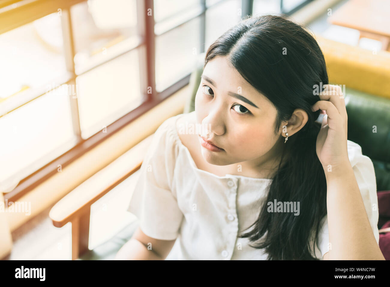 Asian teen girl looking pregunta y rascarse la cabeza de pérdida de memoria o confundir Foto de stock
