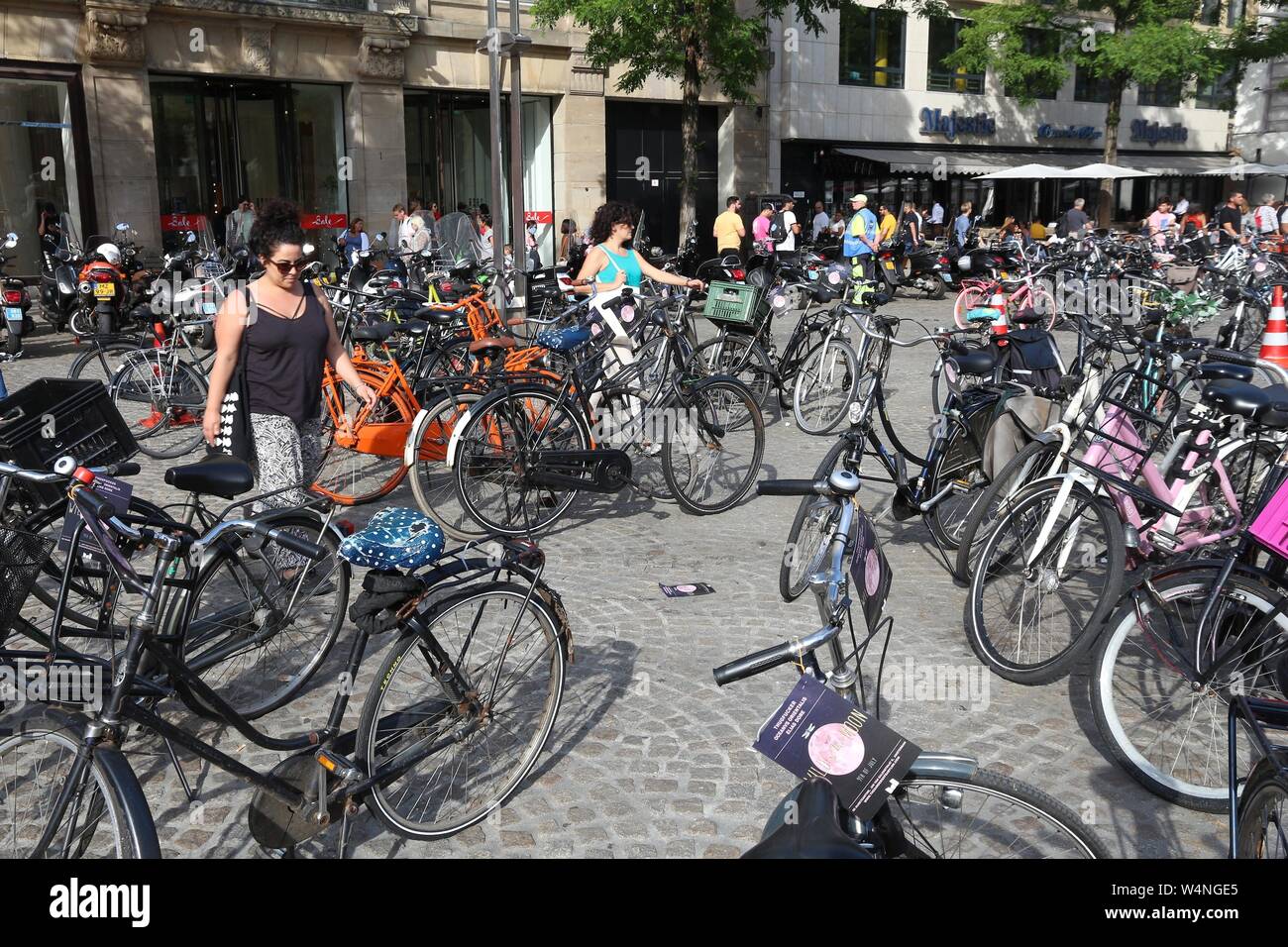 AMSTERDAM, Holanda - Julio 9, 2017: la gente camina a través de aparcamiento de bicicletas en la Plaza Dam en Amsterdam, Países Bajos. Ámsterdam es la ciudad capital de T Foto de stock
