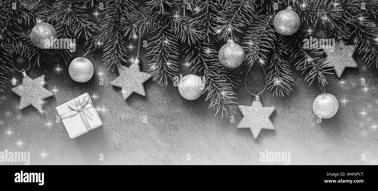 Navidad frontera abstracta en blanco y negro con un tono plateado, ramas de abeto decorado con bolas y estrellas. Vista superior, laicos plana Foto de stock