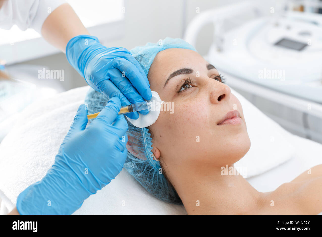 Clínica de estetica profesional estético con bata de laboratorio que  realiza un procedimiento de relleno de ácido hialurónico en una paciente