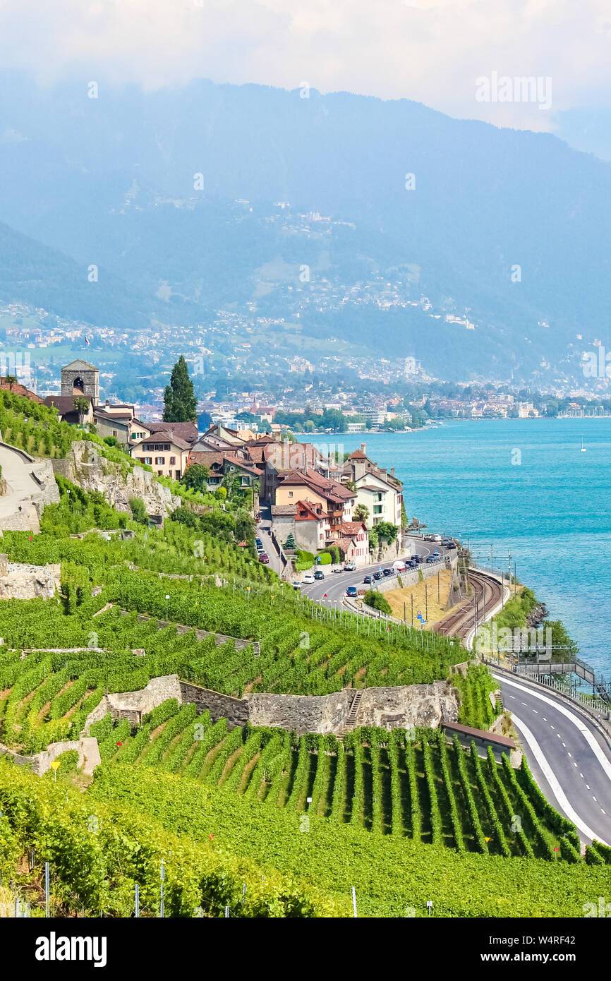 Foto vertical del bello pueblo de St. Saphorin vitivinícola en la región vinícola de Lavaux, en Suiza. Temporada de verano suizo. Sorprendente Lago Ginebra en segundo plano. Los viñedos en las terrazas junto al lago. Los paisajes de Suiza. Foto de stock