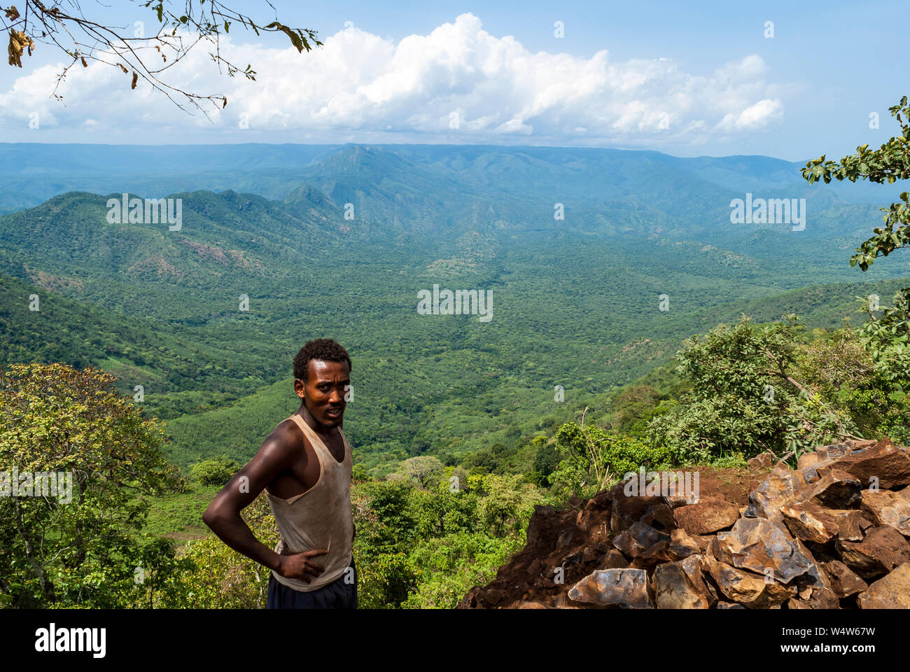 El hombre etíope está en acantilado cerca de Bure , Illubabor, Etiopía, con bosques de tierras bajas paisaje en segundo plano. Foto de stock
