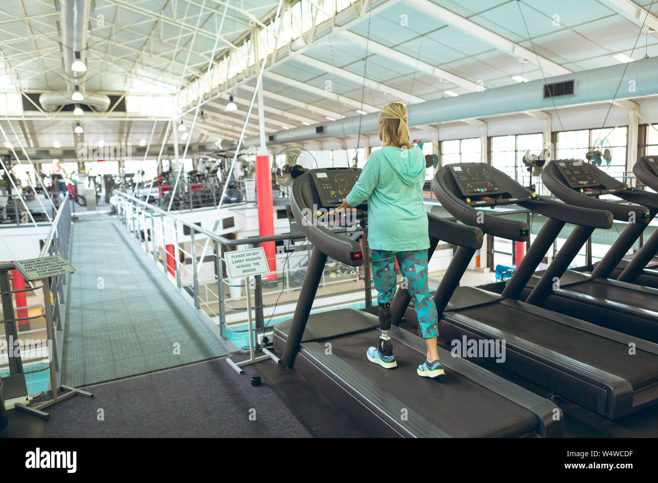 Ajuste a la mujer con auriculares y dispositivo móvil escuchando música en  la máquina de correr en el gimnasio Fotografía de stock - Alamy