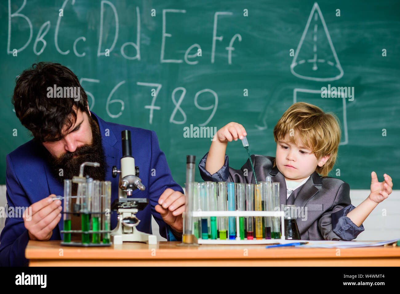 El conocimiento es deliciosa. La escuela kid científico que estudia la ciencia. maestro Hombre con Little Boy. Al regresar a la escuela. El padre y el hijo en la escuela. Chiquillo aprender química en la escuela laboratorio. Foto de stock