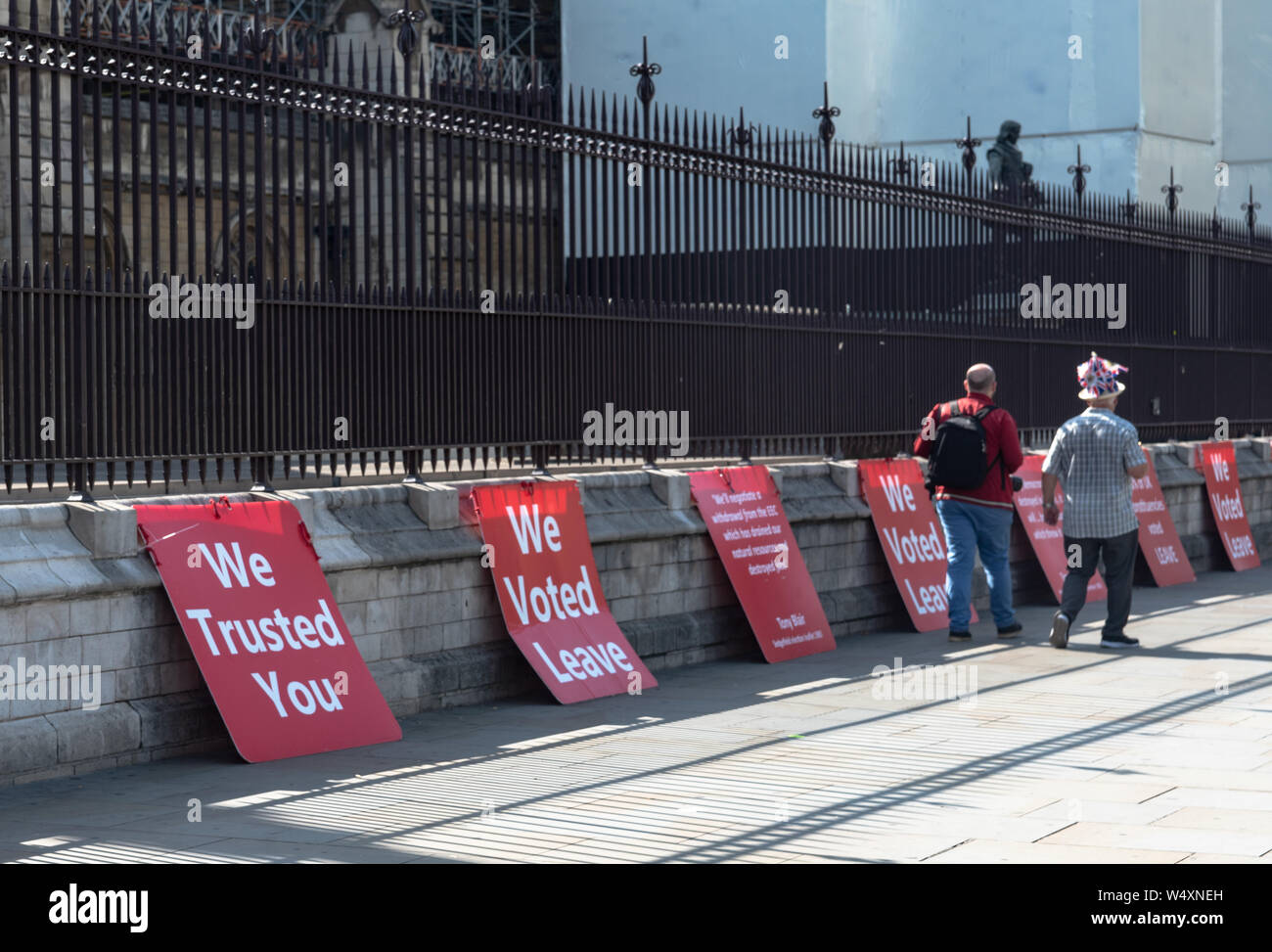 Westminster, Londres, Reino Unido 24 de julio. Votación para dejar carteles colocados a lo largo de una pared. Dos hombres caminando por una union jack vistiendo un sombrero. Foto de stock