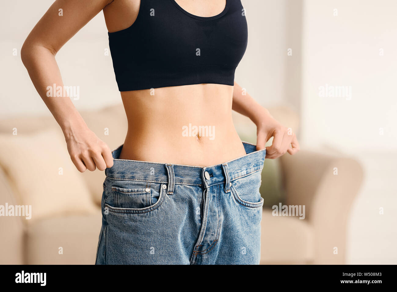 Mujer en pantalones vaqueros flojos en casa. Concepto de pérdida de peso  Fotografía de stock - Alamy