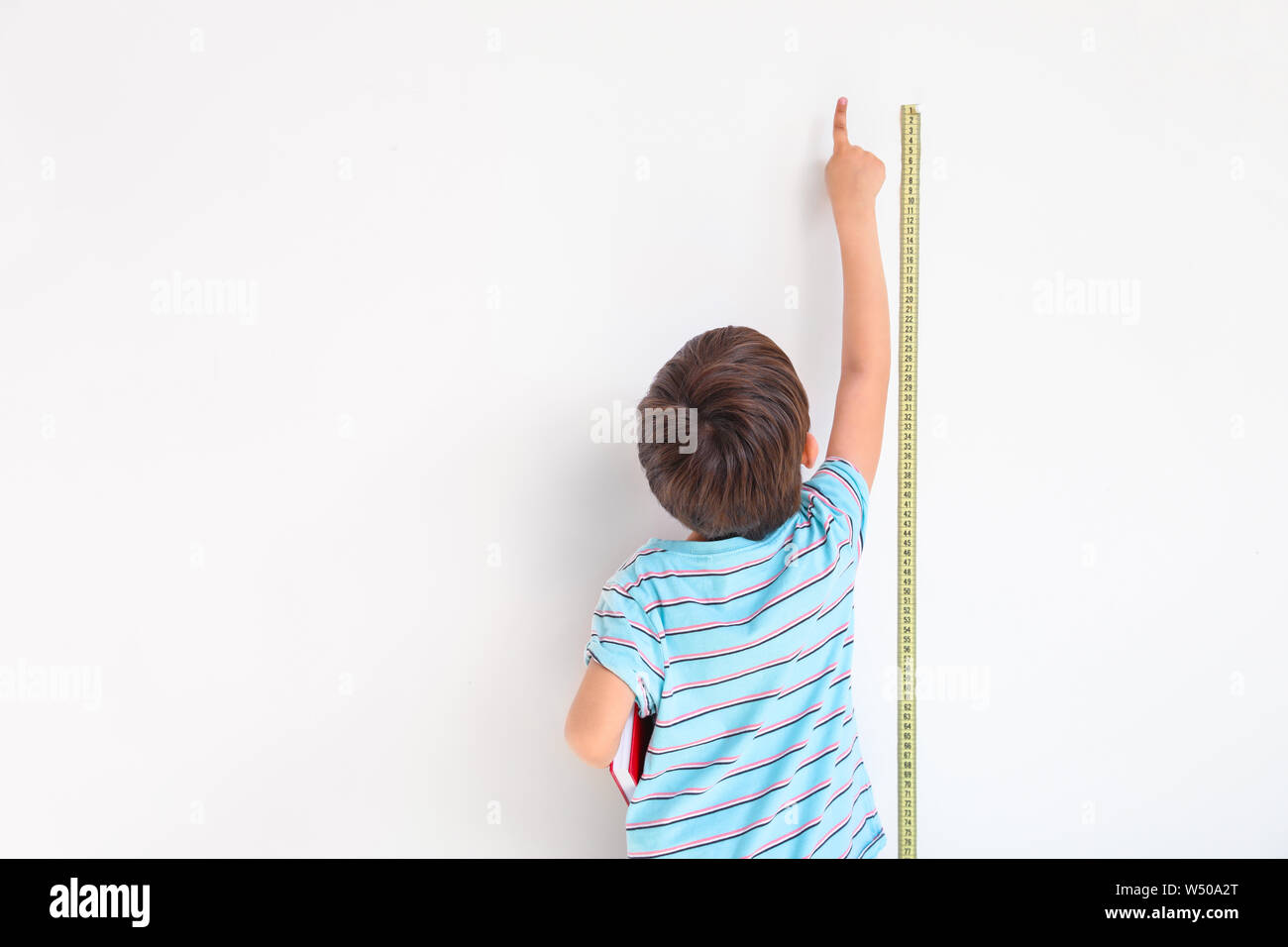 Cute Little Boy Medir La Altura Cerca De Pared Fotografia De Stock
