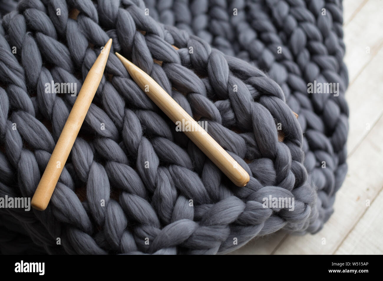 Agujas de tejer de madera sobre fondo gris de manta de lana merino  Fotografía de stock - Alamy