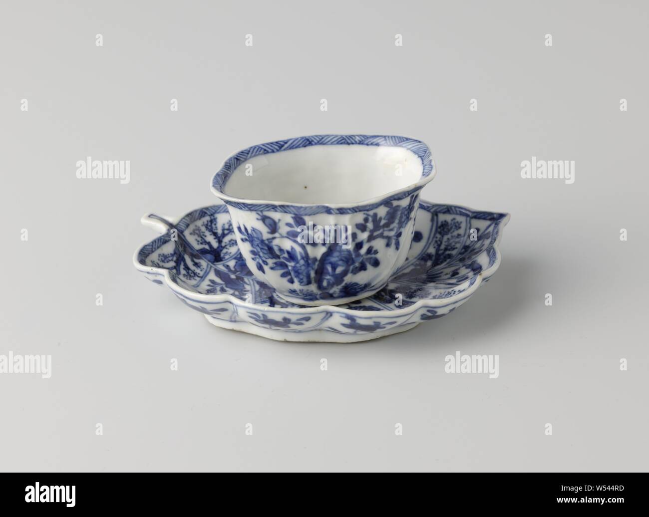 Taza con platillo en forma de una hoja, taza y plato de porcelana, el platillo en la forma de una hoja, pintado de azul underglaze. La cabeza modelada con venas en el exterior y pintados con una rama de flores flores cuatro veces, una rama de flores en la parte inferior, el interior y el exterior del borde con una banda decorativa con la eclosión. El plato está dividido con una caja decoración por los "ins" de la hoja, llena de diversas plantas en floración en una roca. Marcados en la parte inferior del plato con un lotus. Azul Blanco., anónimos, China, c. 1750 - c. 1774, la dinastía Qing (1644-1912) / Periodo Qianlong (1736-1795 Foto de stock