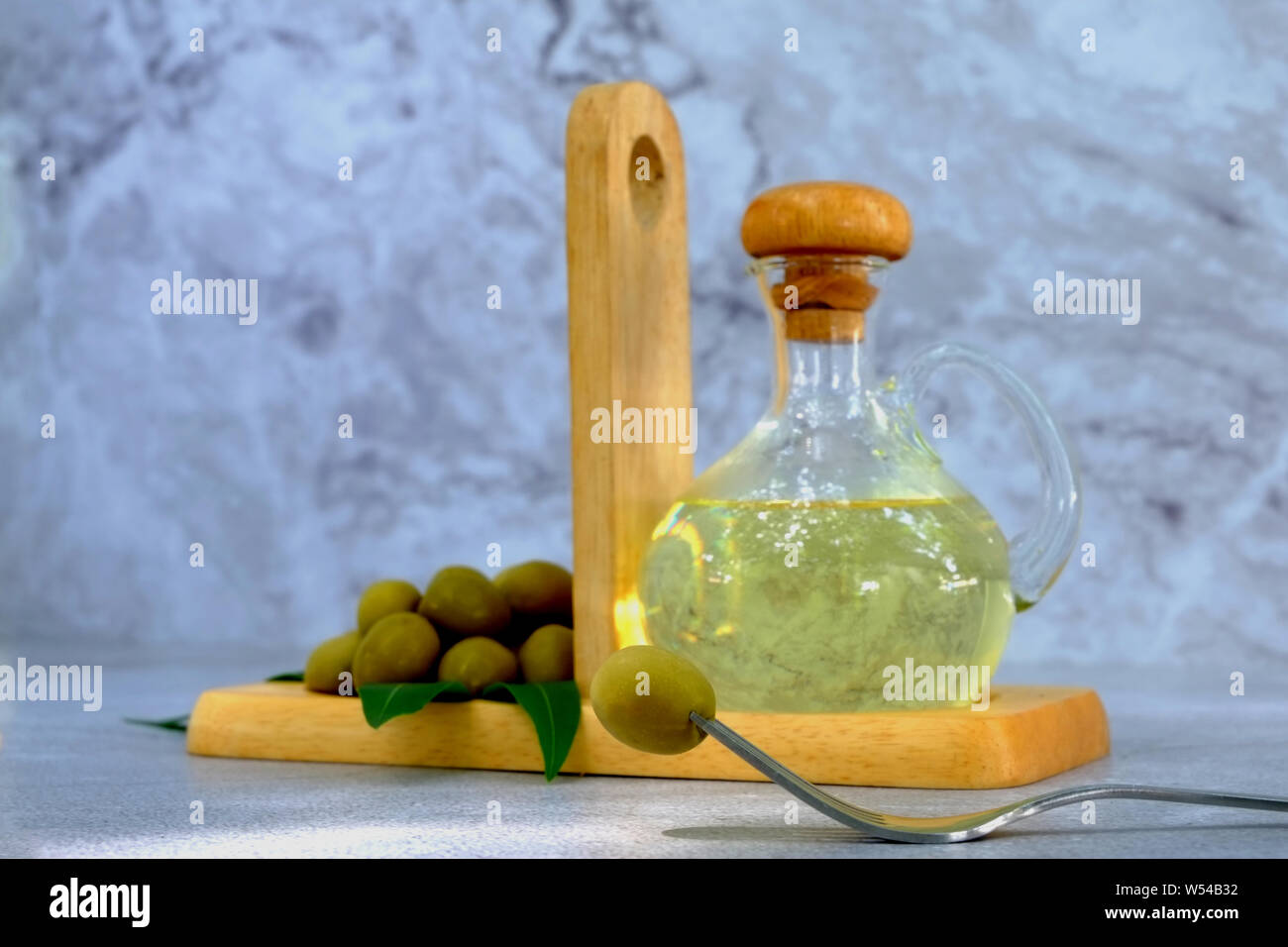 Closeup horquilla con aceitunas, aceite de oliva y Conjunto de hoja sobre  fondo de mármol, frasco de vidrio con aceite de oliva sobre la mesa de  cemento Fotografía de stock - Alamy