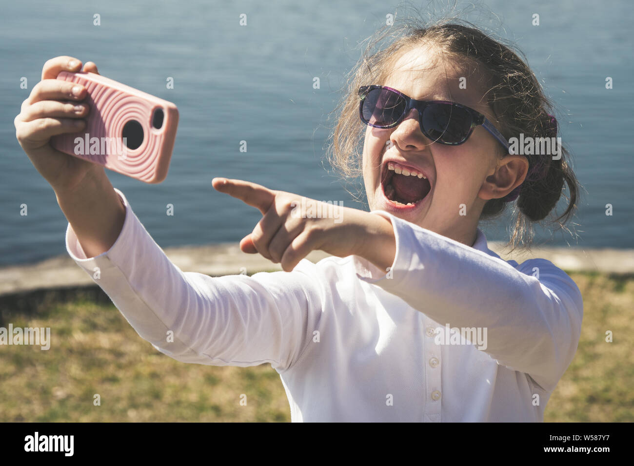 Niña hacer una videollamada con amigos tecnología inalámbrica remota ayuda a mantenerse conectado en cualquier lugar. Hermosa sonrisa kid e indica con el Foto de stock