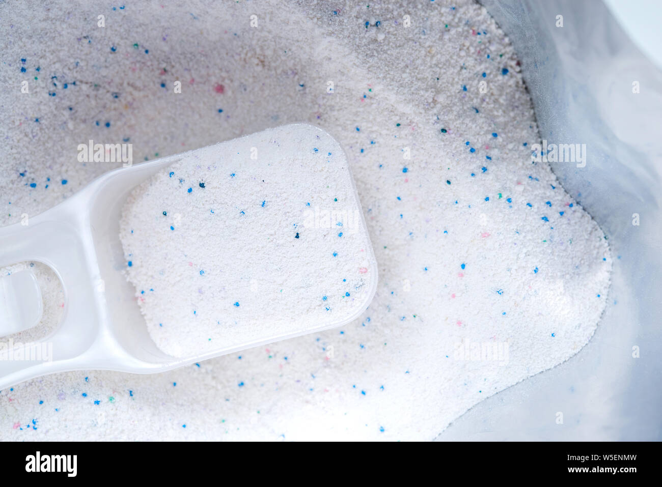 Detergente en polvo con taza de medir en una bolsa de polvo de lavado Foto de stock