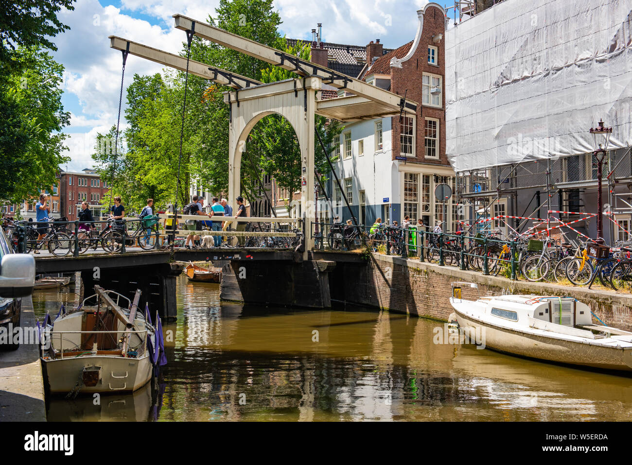 Vista de los canales de Ámsterdam con puente levadizo barcos y turistas Foto de stock