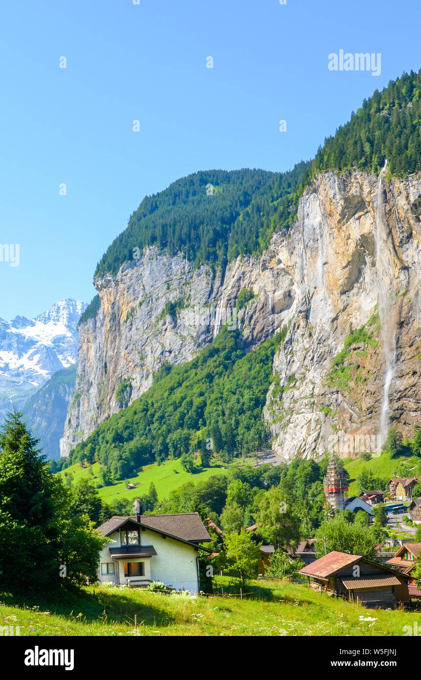 La fotografía vertical del pintoresco pueblo de Lauterbrunnen en los Alpes Suizos. Famoso Staubbach cae en segundo plano. Los turistas destinos en Suiza. La temporada de verano. Los paisajes de Suiza. Foto de stock