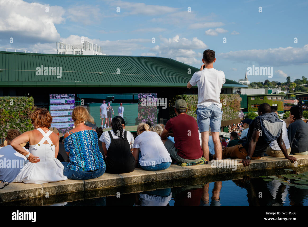 Los aficionados y espectadores de Henman Hill , Murray montículo o Aorangi Hill, con la gran pantalla el nº1 Corte durante el Campeonato de Wimbledon 2019. Foto de stock