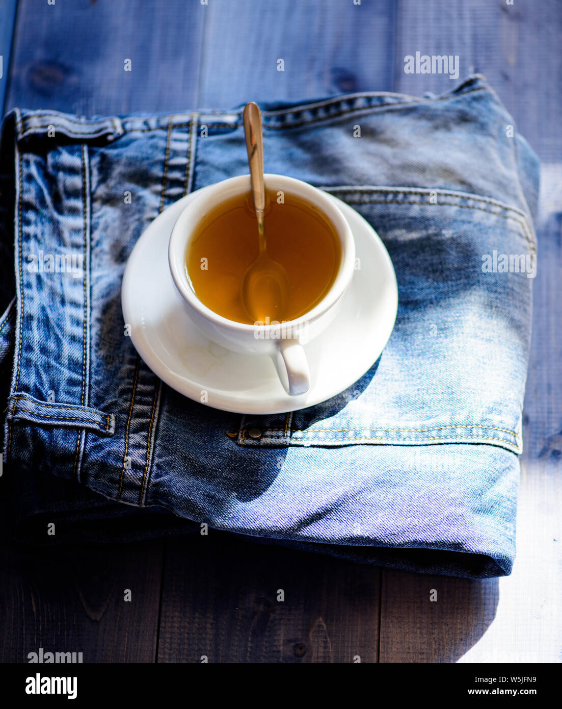 La taza llena de agua hirviente y bolsa de té en el blue jeans de fondo.  Proceso té en taza de cerámica. Hierbas toda la hoja de color verde o  negro. Los