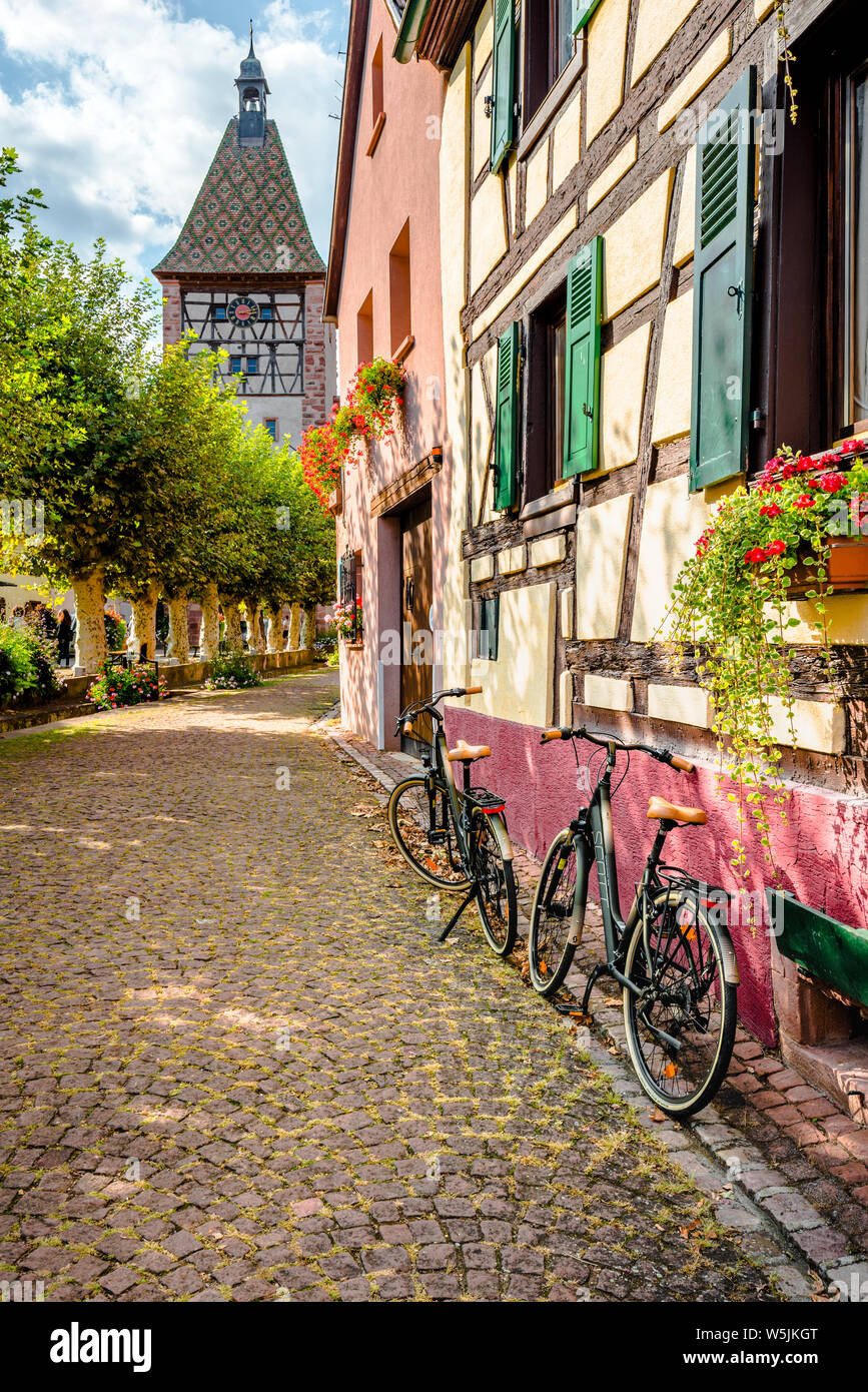 Casco antiguo de la aldea Bergheim con la puerta de la ciudad, la Ruta del Vino de Alsacia, Francia, cobblestone lane y callejón con bicicletas Foto de stock