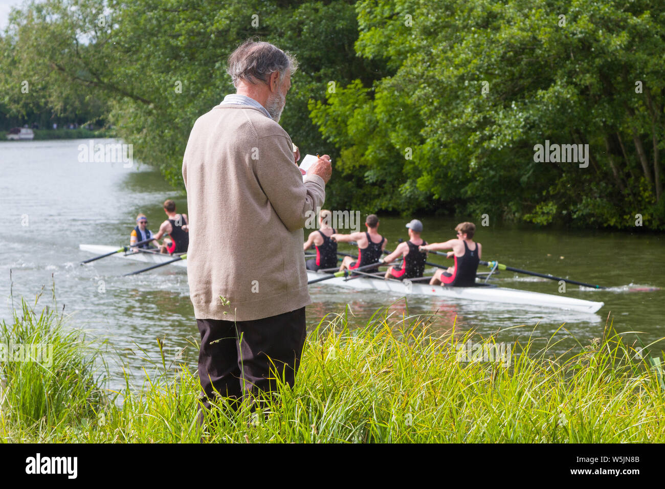 Un hombre toma notas mientras ve una tripulación haciendo su camino al iniciar durante el Oxford ochos Semana. Foto de stock