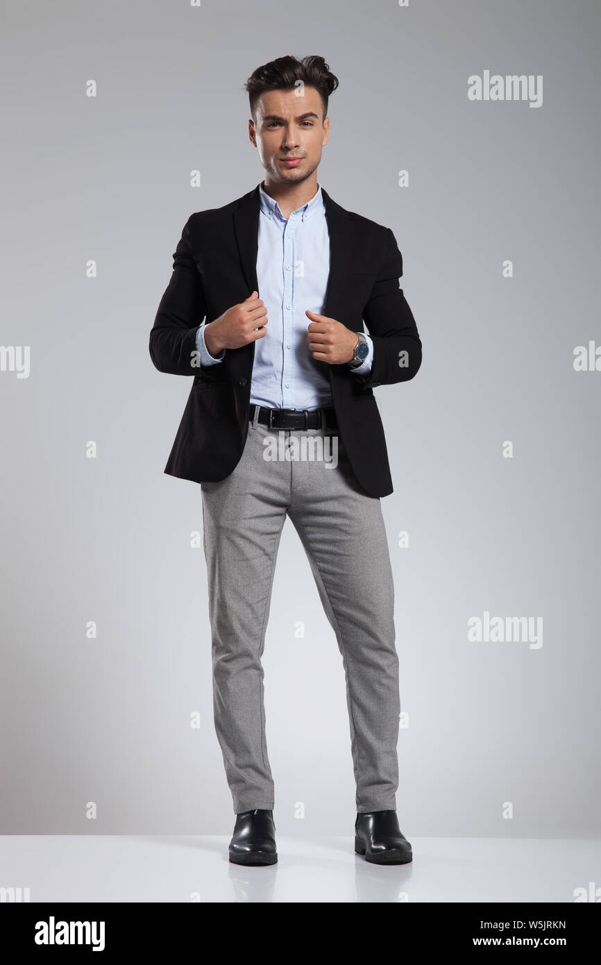 Guapo elegante casual hombre en traje negro de pie sobre fondo gris claro y  la celebración de collar, imagen de cuerpo completo Fotografía de stock -  Alamy