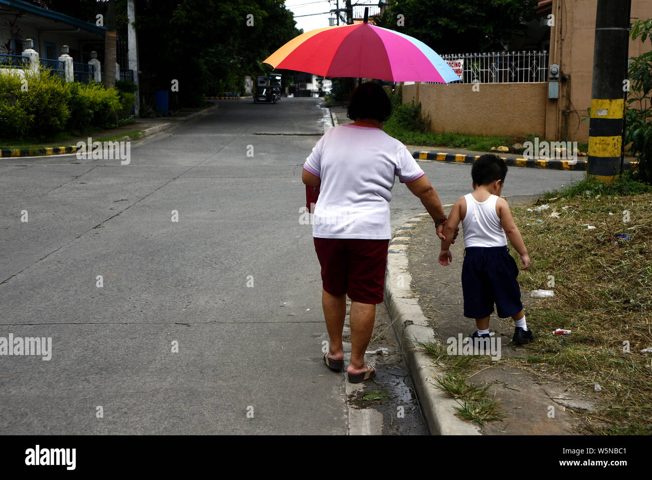 ANTIPOLO CITY, Filipinas - 25 de julio de 2019: Una mujer sostiene la mano de un niño mientras caminaba por una acera de la calle. Foto de stock